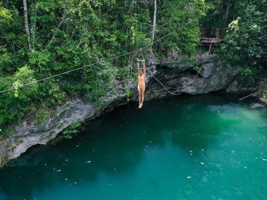 CENOTE ZAPOTE - A GIRL ON A ZIPLINE ABOUT TO JUMP IN THE CENOTE