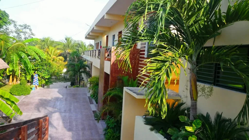 Modern building surrounded by lush greenery and palm trees in a tropical environment.