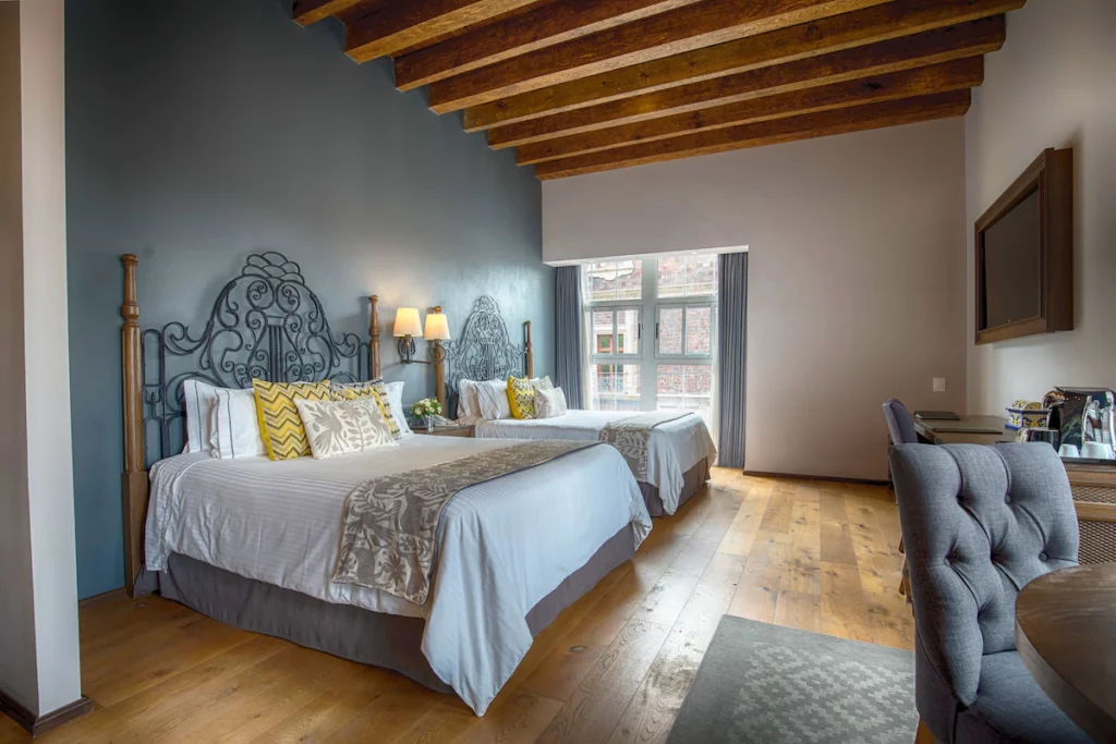 Superior room in Zocalo Central with cozy beds and tables and chairs.