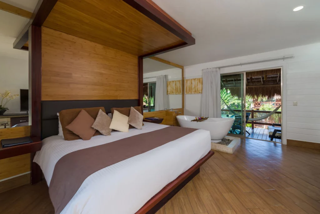 A comfy bed near the tub in a hotel room in Magic Blue Spa Hotel.