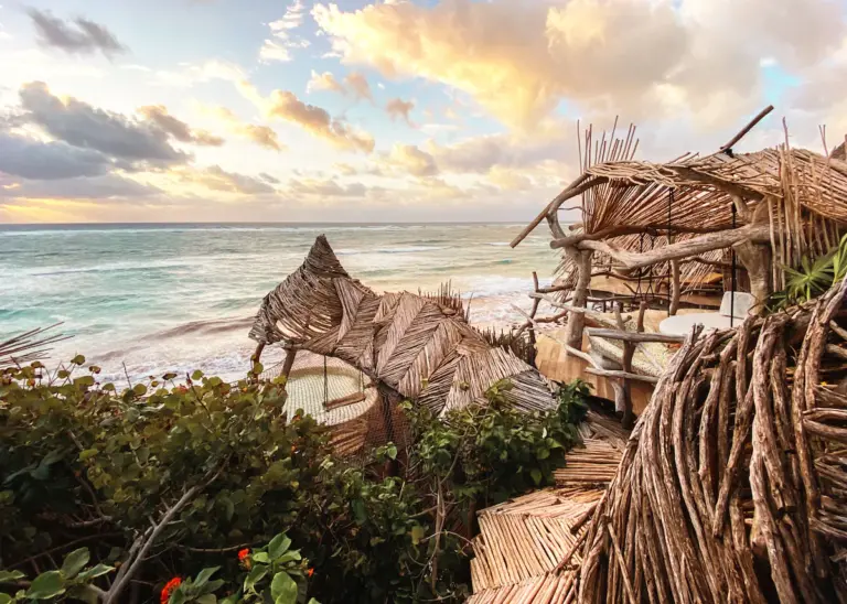 Wooden beach huts overlooking ocean at sunset.