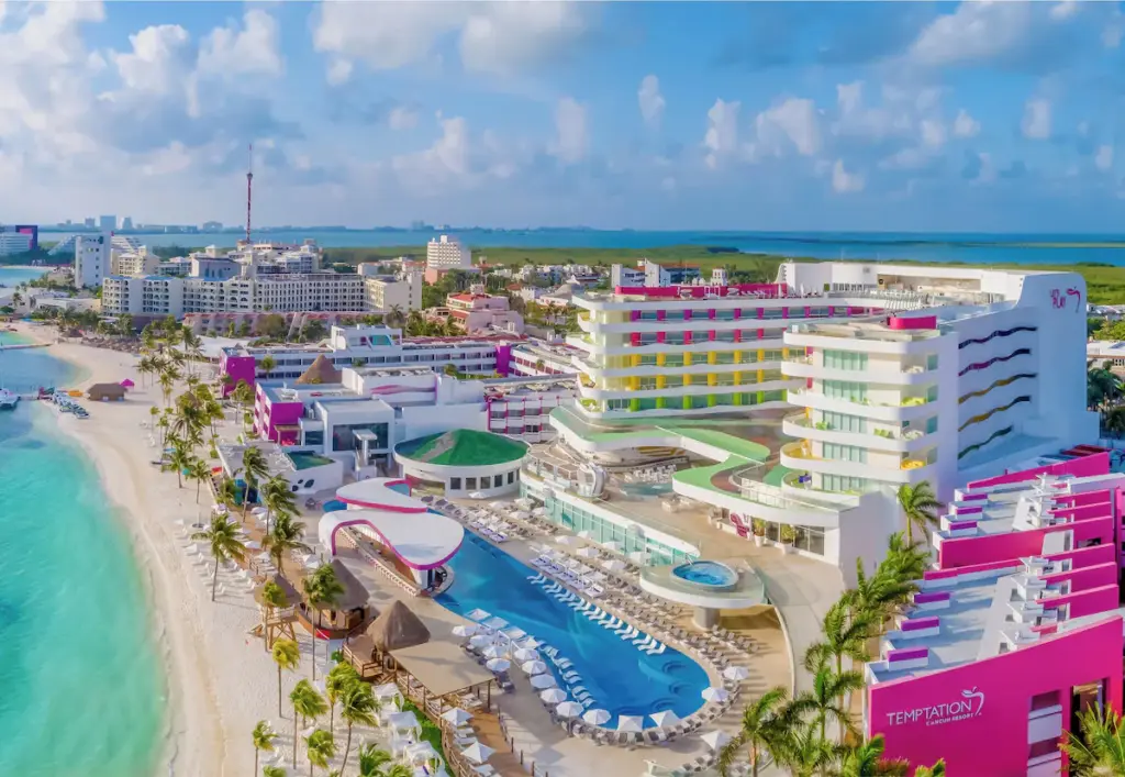 Vibrant beachfront resort with pool and colorful buildings.